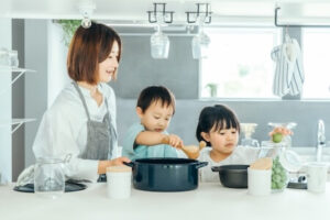 おしゃれなキッチンで料理をする女性とお手伝いする子供たち
