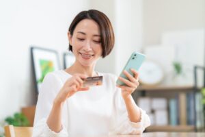 クレジットカードとスマホを持つ日本人女性