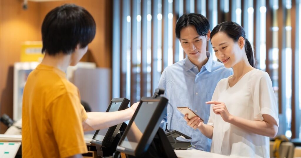 店舗でスマートフォン決済を行うカップル