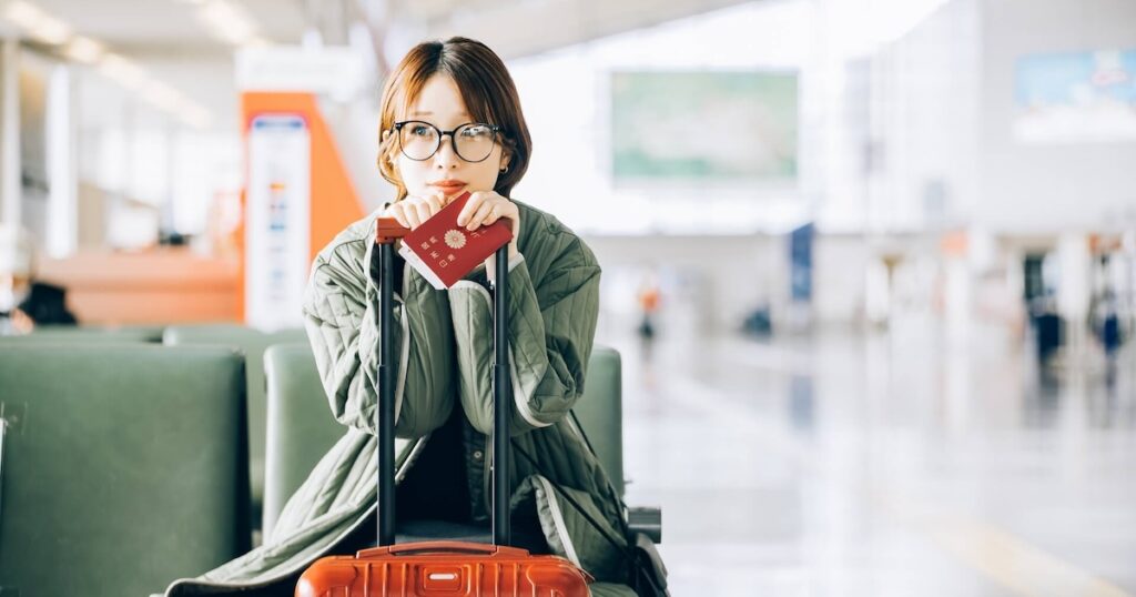 空港のベンチに座る日本のパスポートを持つ女性