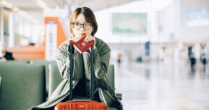 空港のベンチに座る日本のパスポートを持つ女性