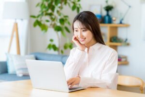 自宅でノートパソコンを見ている若い日本人女性